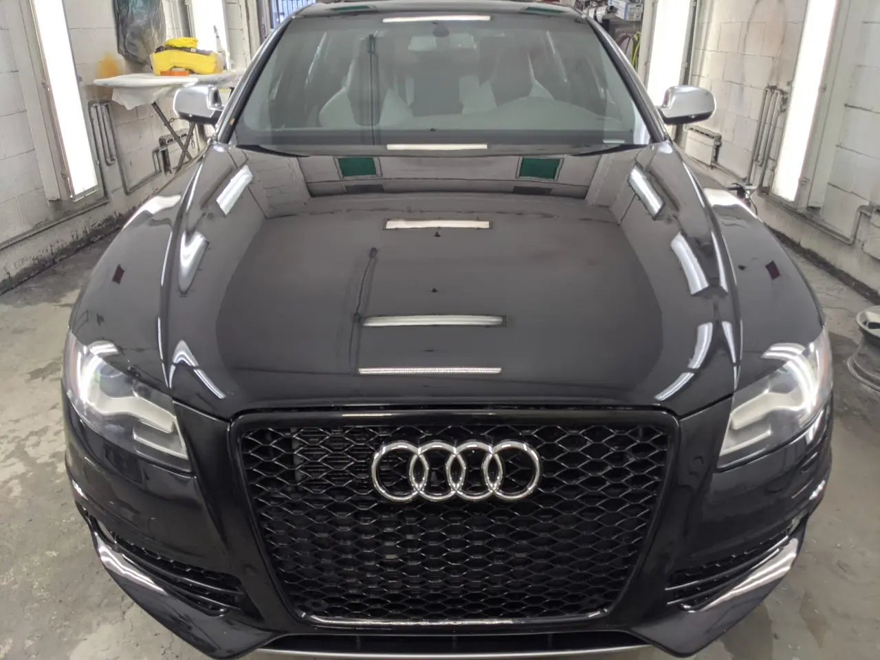 Audi noire vue de face, capot fraîchement peint, ruban de masquage encore en place