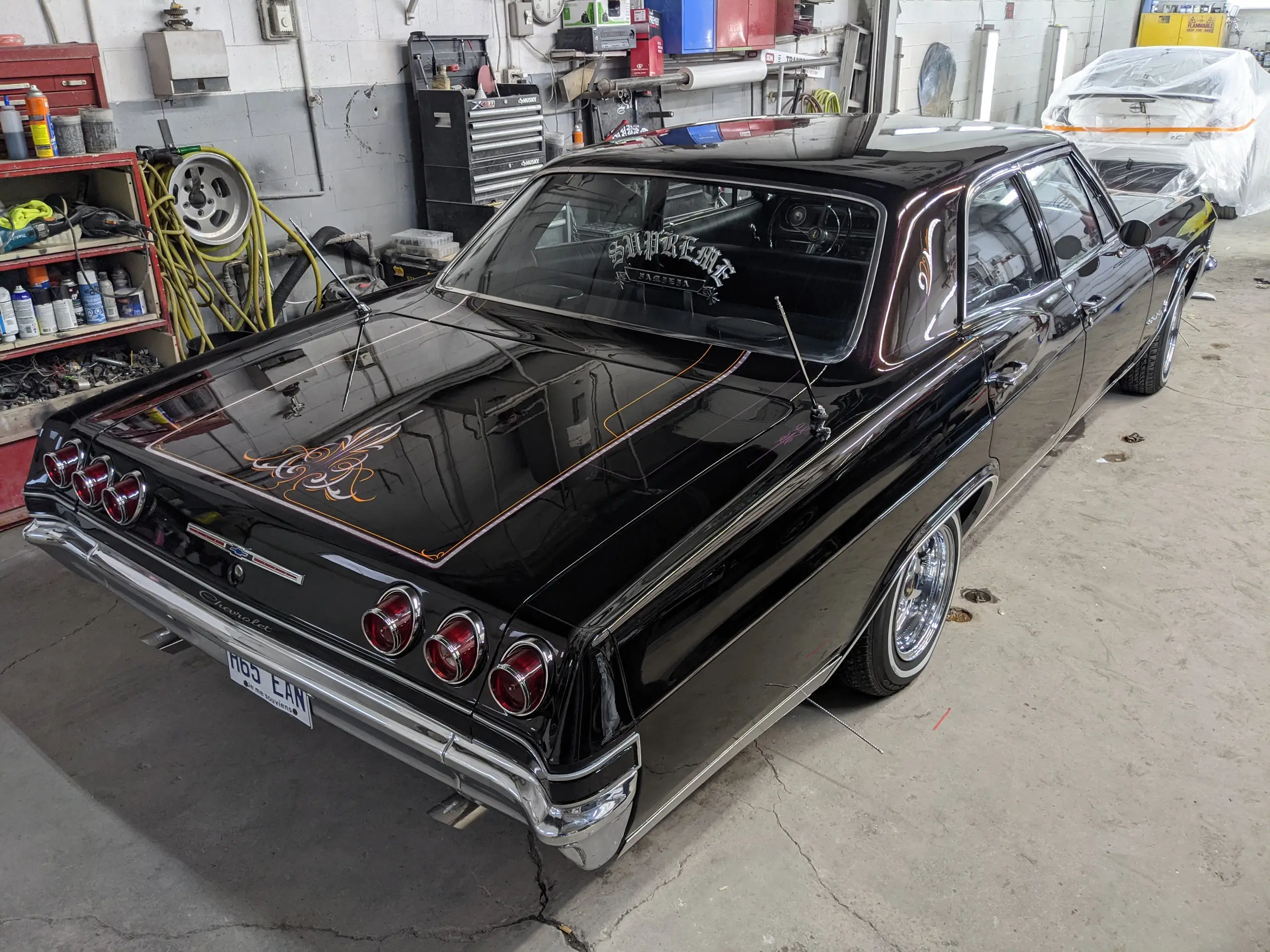 Arrière d’une Chevrolet Impala noire aux filets cuivrés et au chrome poli, à l’atelier SLM Auto