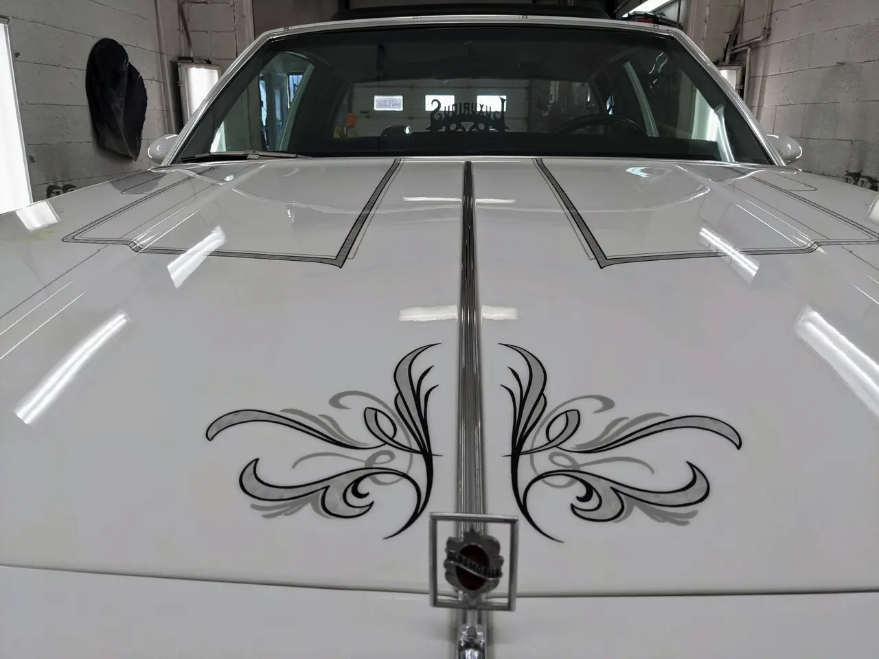 Filets noirs et gris peints à la main sur le capot blanc d’une Oldsmobile Cutlass